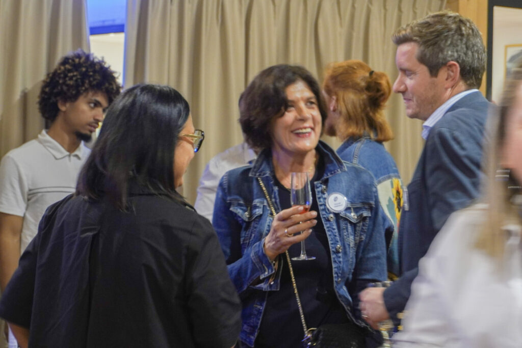 Pascale Tonicello, au centre, sourit et échange avec deux participants, un verre à la main, lors de l’apéritif au Véloscope.