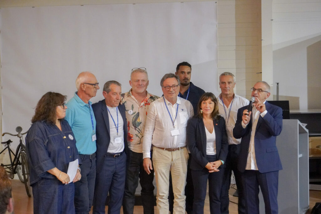 Huit personnes réunies au Véloscope lors de la soirée de La Mêlée Ouverte dans le Gers, Michel Roudière à droite prenant la parole au micro.